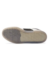 Black and white shoe sole with a textured rubber design; translucent sections reveal a geometric pattern, providing grip and stability.
