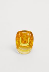 Amber-colored translucent ring with a rounded design, featuring measurement markings inside. Smooth texture with glossy finish.