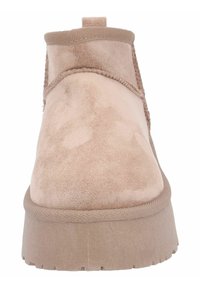 Bottines beige clair en suède doux. Elles présentent un bout rond, une semelle épaisse et des accents cousus le long de la tige pour ajouter de la texture.