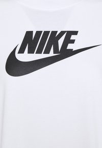 T-shirt bianco in cotone con un grande logo "NIKE" nero e un grafic o swoosh sottostante, texture liscia e scollo rotondo.