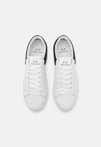 Hvite lær sneakers med svarte hælakkenter, med en strukturert overflate, flate lisser og merkevare på tungen.