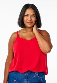 Czerwona bezrękawnik z falbaniastym dekoltem, gładką teksturą i luźnym krojem, zestawiony z dżinsowymi szortami z haftowanymi akcentami truskawek.