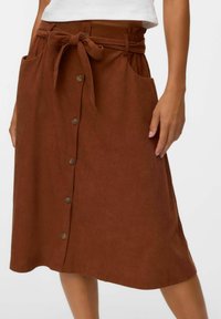 Jupe en velours côtelé marron avec une ceinture à nouer, poches avant et fermetures à boutons sur le devant. Texture lisse avec un design mi-long.