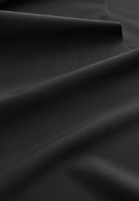 Czarna tkanina na gładkiej powierzchni, z delikatną teksturą i fałdami, prezentująca jednolity kolor bez wzorów czy zdobień.