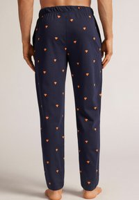 Marina pyjamasbyxor med elastisk midja, prydda med spridda orange diamantformade mönster. Mjukt, lätt tyg med en avslappnad passform.
