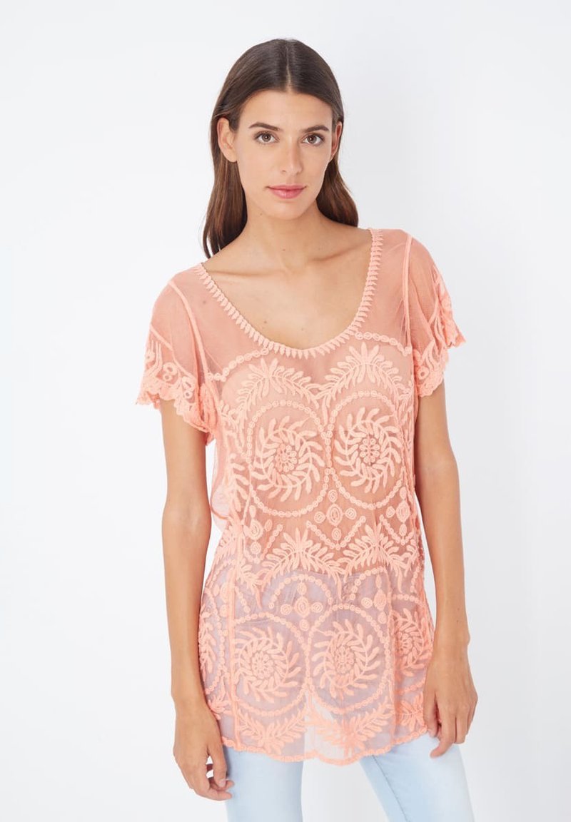 Top bordado en melocotón con escote redondeado, mangas cortas y patrón floral. Tejido transparente con detalles delicados y bordes ondulados.