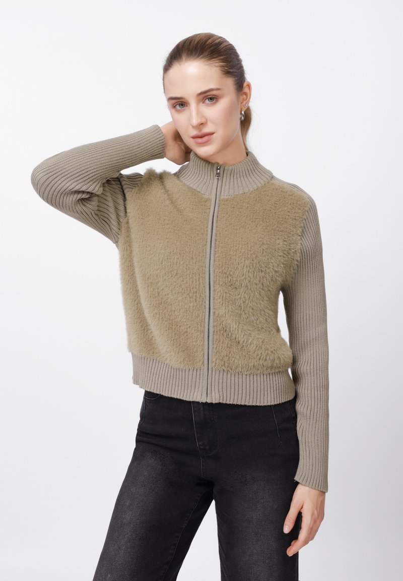 Φούτερ με φερμουάρ σε ανοιχτό πράσινο ελιάς, με υφή αφράτου υφάσματος στο σώμα και ριμπ μανίκια, με ψηλό γιακά και εφαρμοστή μέση.