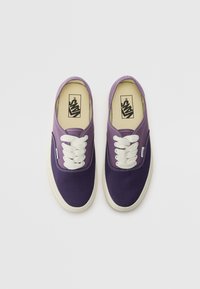 Ljubičaste platnene tenisice s bijelim vezicama, s kontrastnim tamnim prstom, šivenim detaljima i Vans logom na unutarnjoj ulošku.