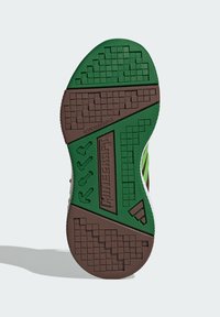 Sól obuvi z farebným zeleným a hnedým gumovým materiálom, s textúrovanými gripovými vzormi a embosovanými detailmi, vrátane nápisu 'NENÁPADNÉ' a akcentov loga.