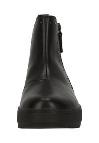 Botas de tobillo de cuero negro con un acabado suave, que cuentan con una cremallera lateral y tachuelas metálicas decorativas a lo largo del borde superior. Suela de goma.