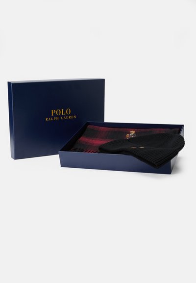 Čierna pletená čiapka a červený károvaný šál prezentované v modrej krabičke, na veku s zlatým textom "POLO RALPH LAUREN".