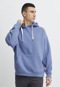 Felpa blu in cotone con tasca a marsupio, cappuccio con coulisse e un piccolo logo sul petto. Presenta polsini e orlo a coste.