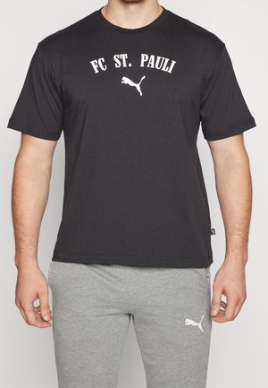 Černé bavlněné tričko s nápisem "FC ST. PAULI" a bílým logem Puma. Jednoduchý design s kulatým výstřihem a krátkými rukávy. Spárováno se šedými tepláky.