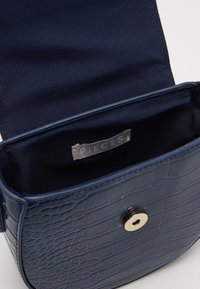 Borsa a tracolla in ecopelle blu navy con un motivo a coccodrillo testurizzato, dotata di una chiusura a scatto in tonalità oro lucido e foderata in morbido tessuto interno.