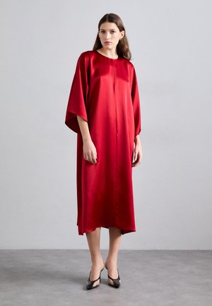 Red satin dress with a relaxed fit, short sleeves, and a round neckline. Features a straight hem and falls below the knee. Worn with black heels.