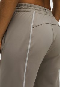 Rövid szárú, szürke, sportos nadrág, texturált felülettel, rugalmas derékpánttal és fehér oldalszegéssel. Nincsenek látható zsebek.