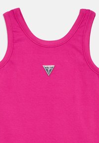 Φούξια τοπ με φαρδιές τιράντες, κατασκευασμένο από βαμβάκι. Διαθέτει ένα μικρό ασημί τρίγωνο λογότυπο με διακοσμητικές λεπτομέρειες στο μπροστινό μέρος.