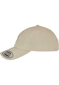 Beige állítható sapka ívelt vizorral, texturált anyagból készült, szellőzőlyukakkal és címkézett folttal az elején.
