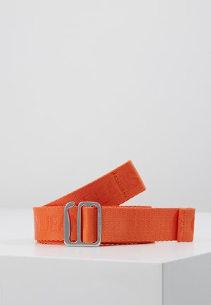 Oranje stoffen riem met reliëftekst en een zilverkleurige rechthoekige metalen gesp, opgerold weergegeven op een wit oppervlak.