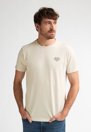 T-shirt en coton beige à texture tachetée, col rond et manches courtes. Logo texte vert sur le côté gauche de la poitrine.