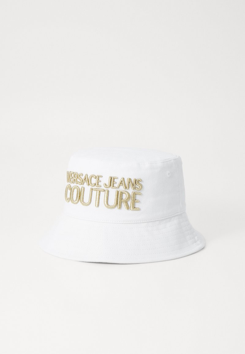 Chapéu de balde branco feito de algodão, apresentando o bordado "VERSACE JEANS COUTURE" em dourado. A aba é larga, com um acabamento em tecido texturizado.