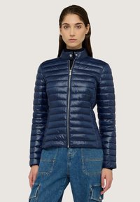 Giacca puffer navy con quilting orizzontale, colletto alto e zip frontale. Tessuto leggero e lucido con vestibilità su misura.