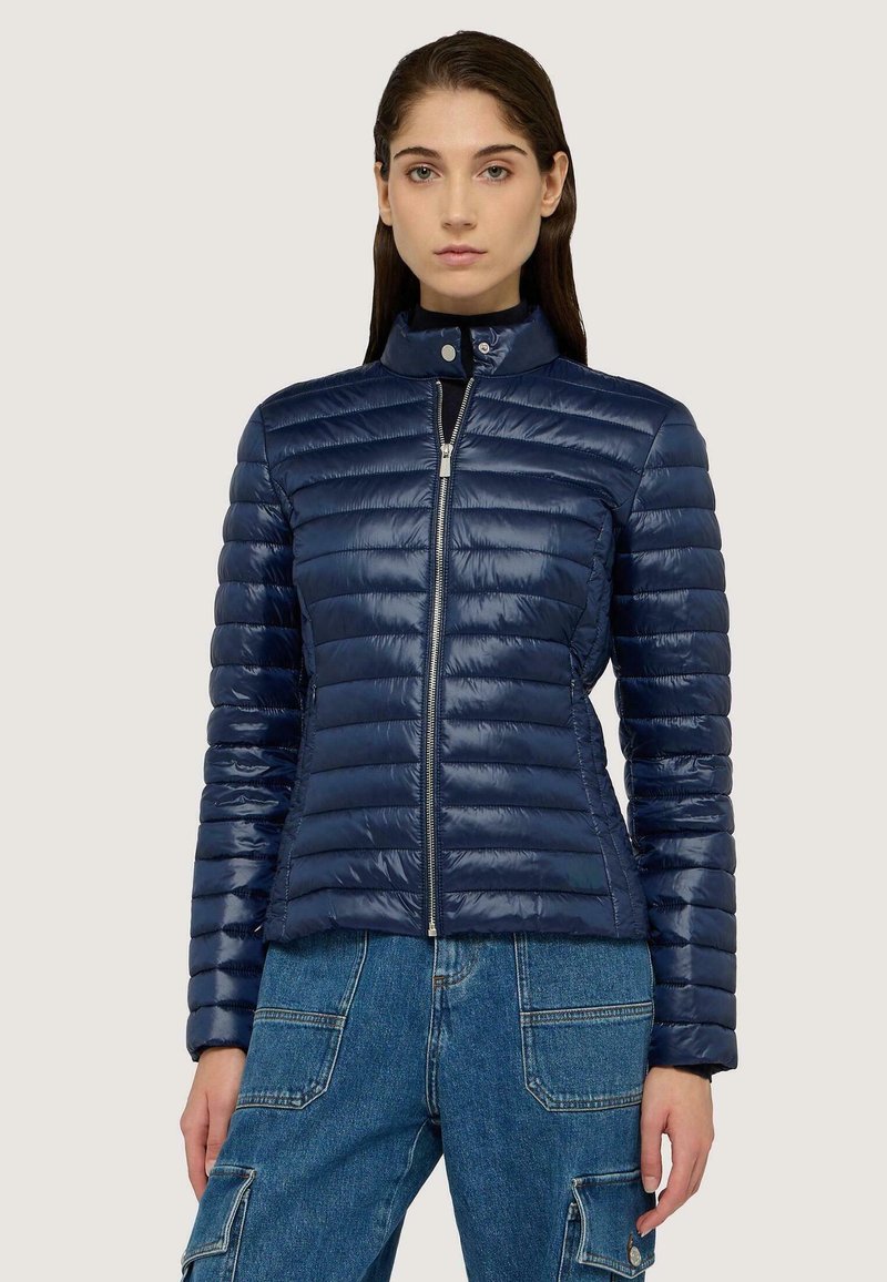 Giacca puffer navy con quilting orizzontale, colletto alto e zip frontale. Tessuto leggero e lucido con vestibilità su misura.