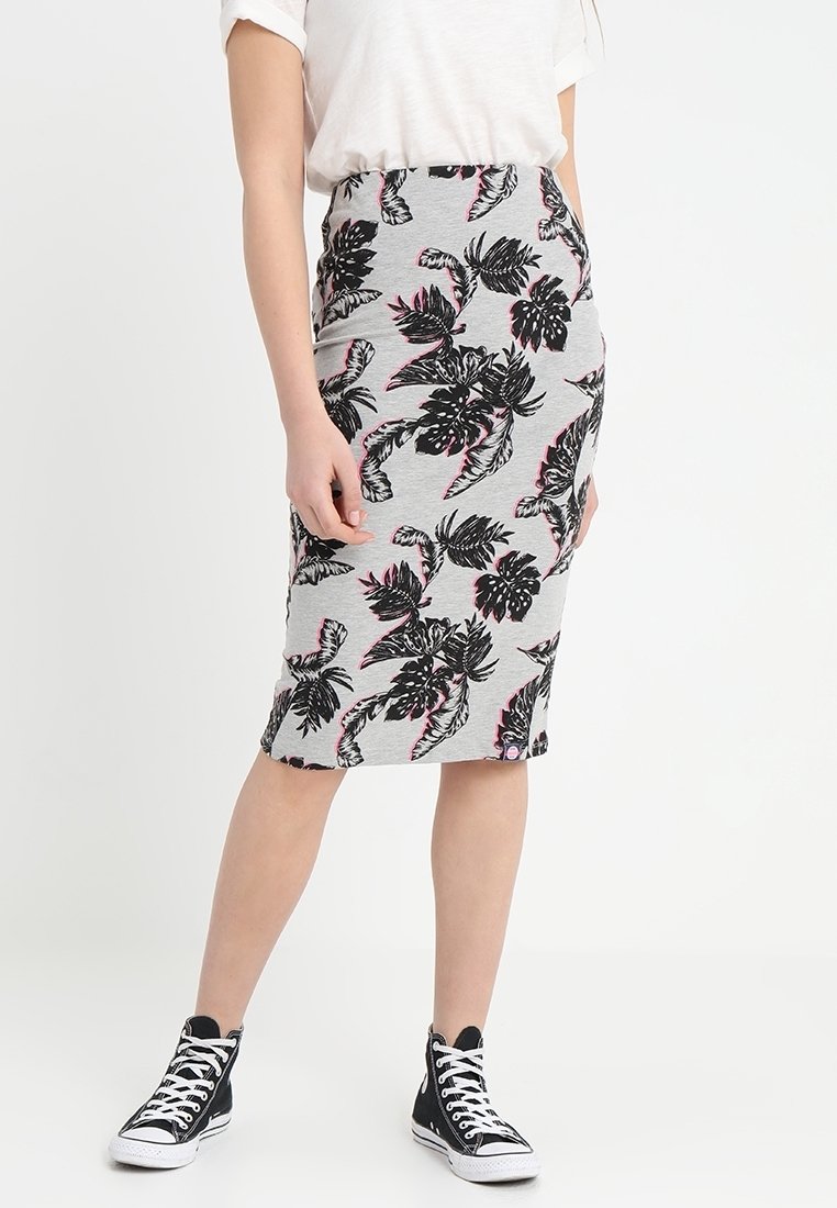 Jupe crayon grise avec un motif de feuilles noires et roses, fabriquée en tissu extensible. Associée à un haut blanc et des baskets montantes noires.