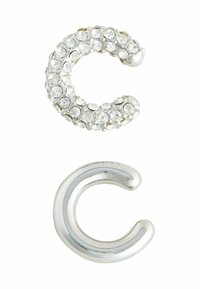 Rhinestone-beklædt sølv 'C' form ovenpå; poleret sølv 'C' form nedenunder. Begge genstande har glatte overflader og rundede ender.