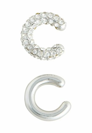 Rhinestone-beklædt sølv 'C' form ovenpå; poleret sølv 'C' form nedenunder. Begge genstande har glatte overflader og rundede ender.