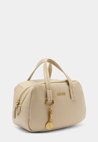 Beige Lederhandtasche mit zwei kurzen Griffen, Reißverschluss und goldenen Beschlägen. Besitzt einen Schlüsselanhänger als Akzent und ein geprägtes Logo auf einer Seite.