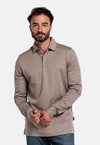 Langärmliges, beiges Poloshirt aus weichem Stoff, mit einem klassischen Kragen, einer Drei-Knopf-Leiste und dezenten Nähten.