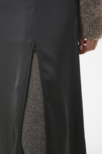 Svart, semi-tett skjørt med glidelås på siden. Stoffet ser glatt ut, mens det indre fôret viser en myk grå tekstur.