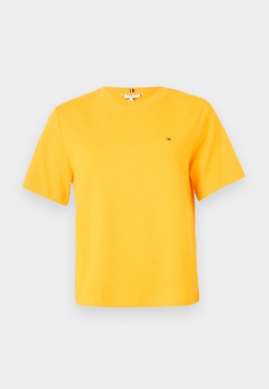 Camiseta amarilla de algodón con cuello redondo, mangas cortas y un pequeño detalle de logo en el pecho. Textura suave y diseño casual.