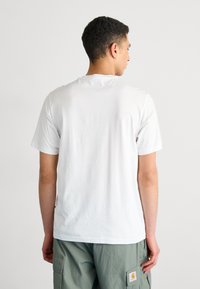 White cotton t-shirt featuring a classic crew neck, short sleeves, and a straight cut, worn with olive green cargo pants.