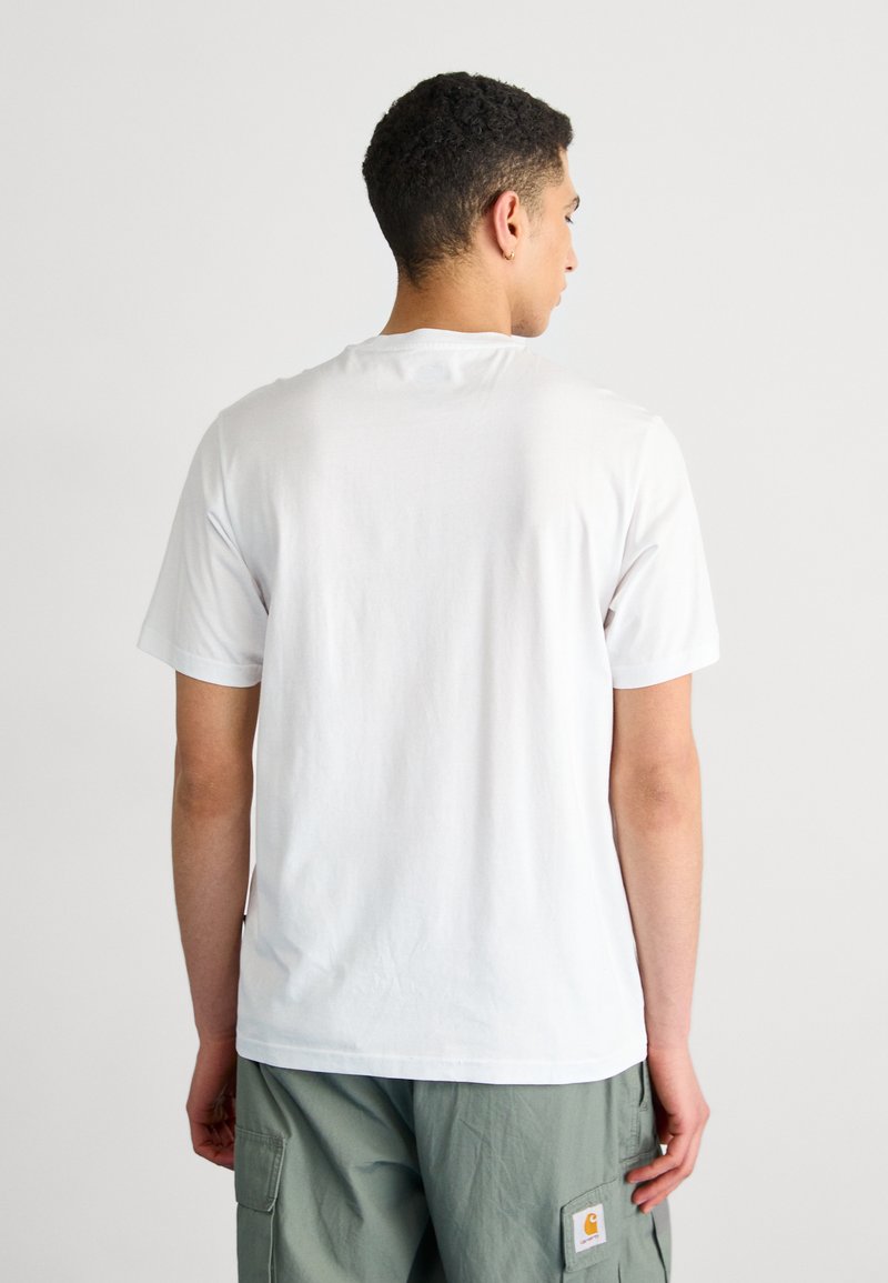 T-shirt bianco in cotone con colletto girocollo classico, maniche corte e taglio dritto, indossato con pantaloni cargo verde oliva.