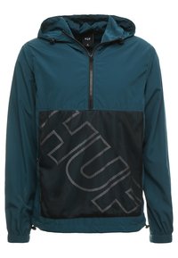 Tyrkysová větrovka s kapucí, s předním zipem a černou síťovanou panely, na které je velké šedé logo. Elastické manžety a lem. Lehký materiál.