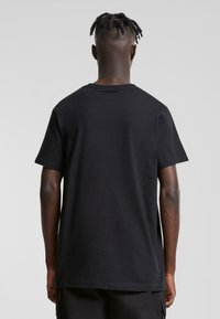 Sort bomulds-t-shirt med et enkelt design, korte ærmer og en standard rund hals, med en blød tekstur og afslappet pasform.