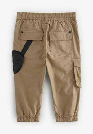 Tan cargo-byxor med elastisk midja, flera fickor, inklusive en sidoficka med svart dragkedja, och elastiska muddar vid anklarna.