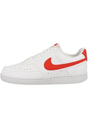 Zapatilla de cuero blanca con un logotipo Swoosh rojo, puntera texturizada y cordones redondos. Presenta una suela de goma sólida con un ligero moteado.