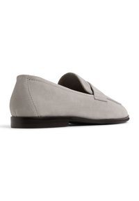 Graue Wildleder-Loafer mit einer flachen braunen Sohle, die an der Vorderseite leicht erhöht sind und eine glatte Oberfläche für ein elegantes Erscheinungsbild bieten.