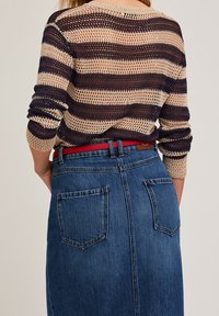 Pull en tricot beige et bleu marine à rayures, avec des manches trois-quarts, associé à une jupe en jean taille haute avec deux poches à l'arrière.