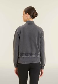 Felpa grigia con fondo e colletto a coste, caratterizzata da una texture morbida e dettagli elastici. Mostrata dal retro con un design slim-fit.