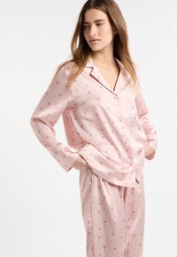 Conjunto de pijama rosa con un patrón a rayas y pequeños estampados florales, hecho de tela suave, camisa con botones y pantalones con cinturilla elástica.