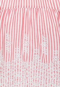 Tissu à rayures verticales rouges et blanches avec une broderie florale blanche le long du bord inférieur.