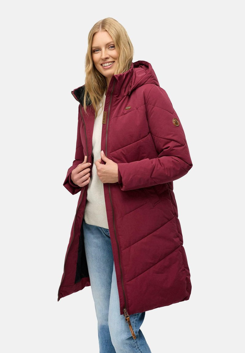 Bordeaux lang puffer-frakke med hætte, der har et quiltet design, lynlåslukning og en tekstureret finish. Brun accentdetalje synlig.