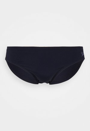 Sötétkék fürdőnadrág puha, rugalmas anyagból, sima kialakítással, minimális varrásokkal és egy logóval az oldalon.