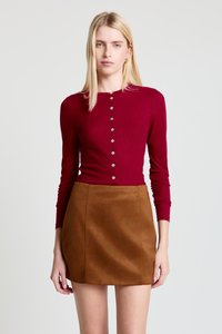 Haut à manches longues côtelé bordeaux avec devant à boutons, associé à une mini-jupe en daim camel. Texture lisse et coupe ajustée.