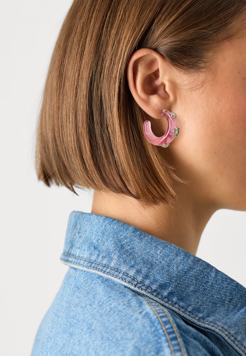 Rosa Acryl-Hoops mit hellgrünen Akzenten, die eine glatte Oberfläche und ein halbtransparentes Design aufweisen.