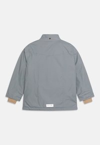 Jasnoszara kurtka z długim rękawem, z beżowymi mankietami wewnętrznymi, guzikiem na tyle kołnierza oraz białą prostokątną metką w pobliżu dolnego brzegu, na białym tle.